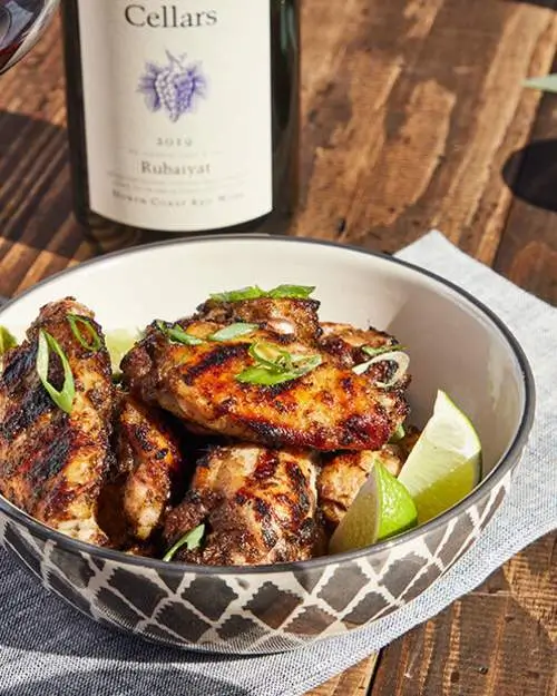 Cooked food in a bowl with a lemon on side and a bottle of wine.